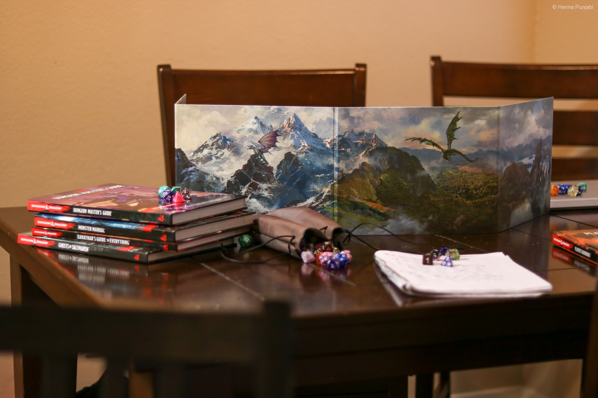 table set up with a gm screen, dice, spell cards, and books, ready to play dungeons and dragons